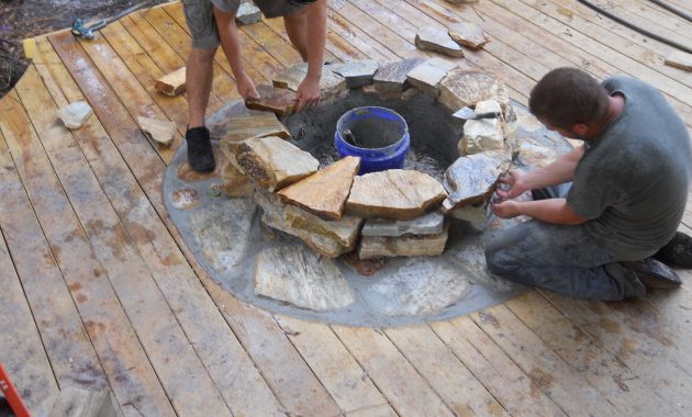 Craftsmen Constructing A Natural Stone Fire Pit On Wooden Deck With throughout sizing 4000 X 3000