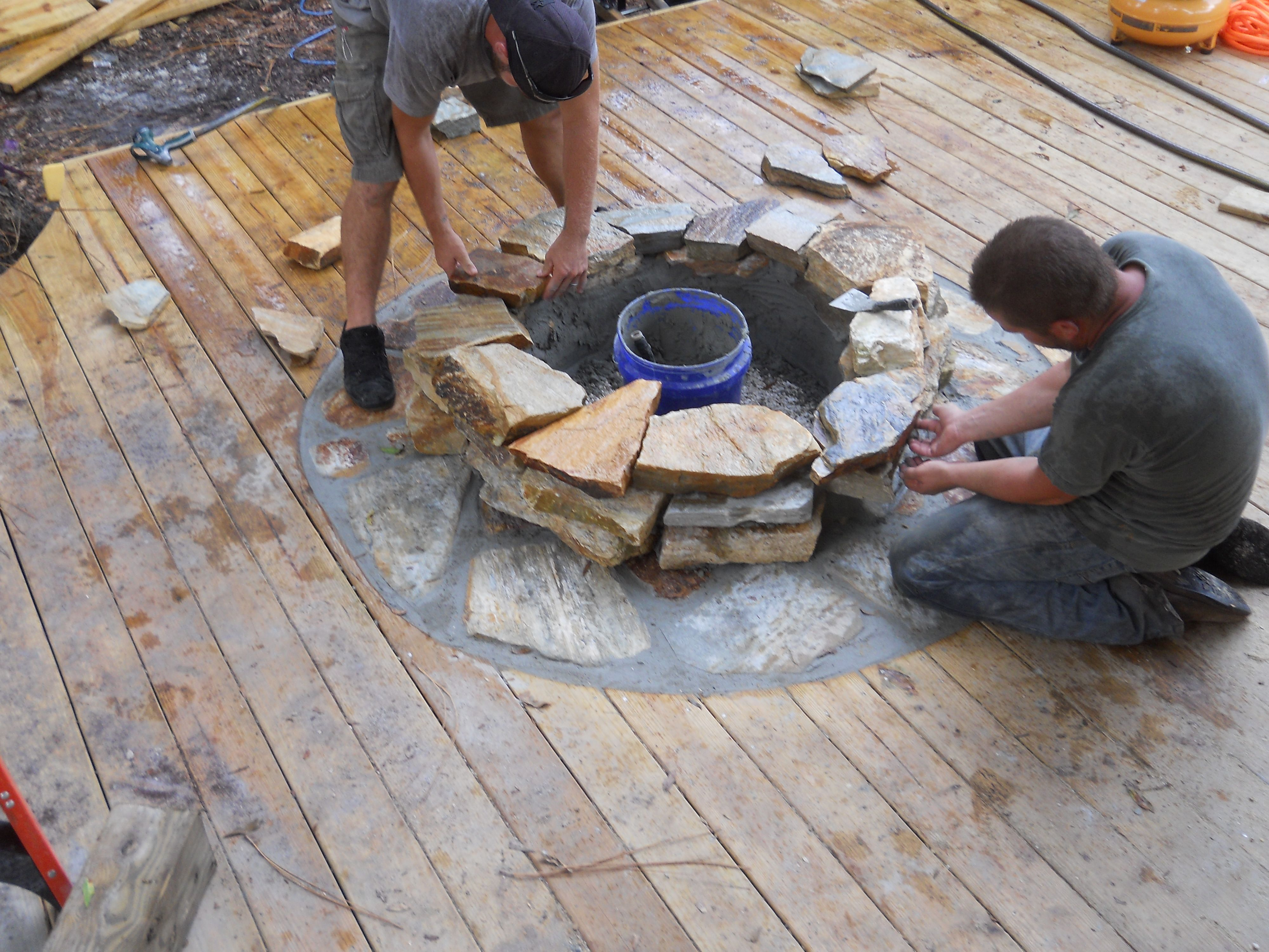 Craftsmen Constructing A Natural Stone Fire Pit On Wooden Deck With throughout sizing 4000 X 3000